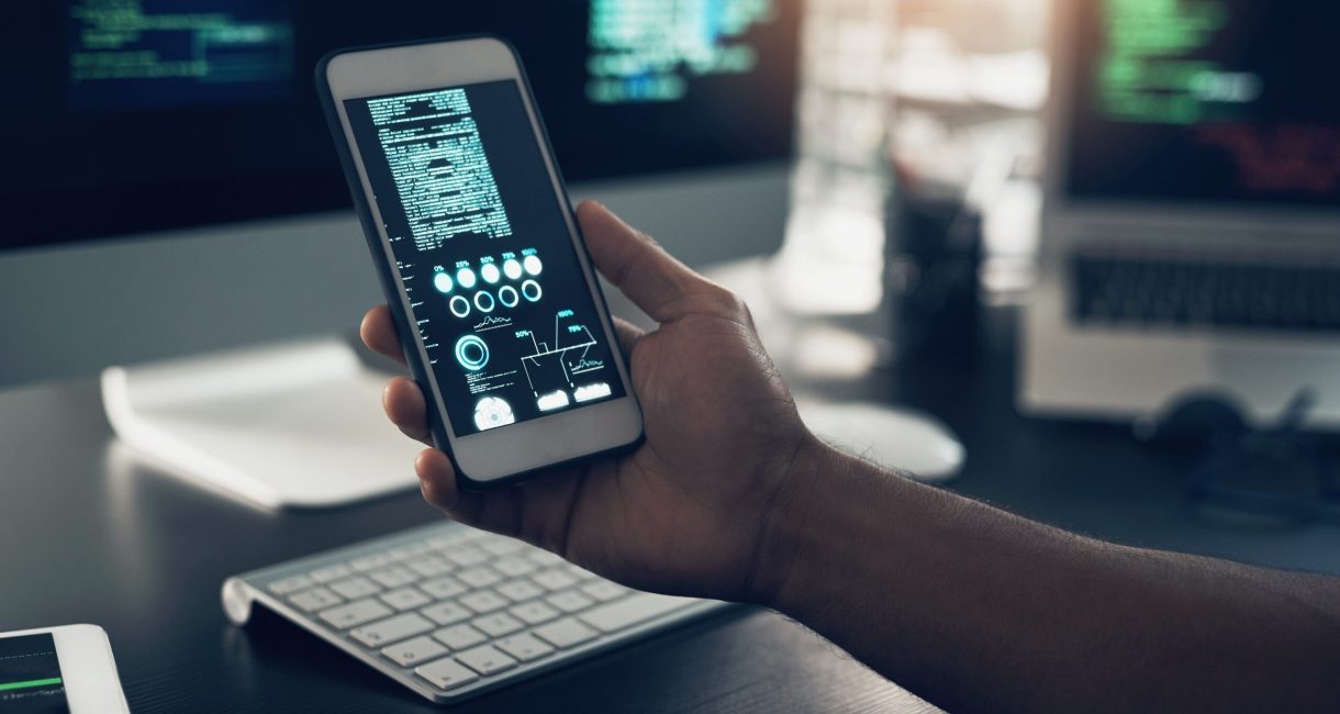 Cropped shot of an unrecognizable man using a cellphone in a modern office.