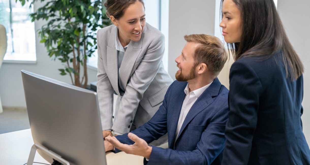 Young successful businesspeople in formalwear discussing presentation in front of computer